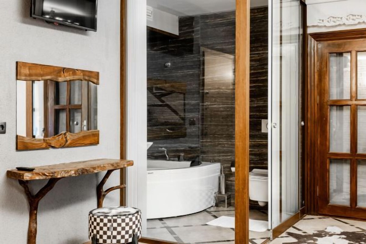 Un baño moderno con una bañera independiente, un tocador con espejo y un reposapiés a cuadros.