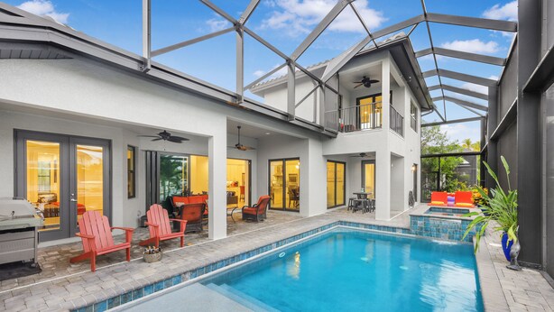 A modern house with a swimming pool, outdoor seating, and a covered patio.