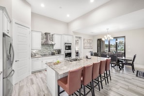 A modern kitchen with white cabinets, a granite countertop, and stainless steel appliances.