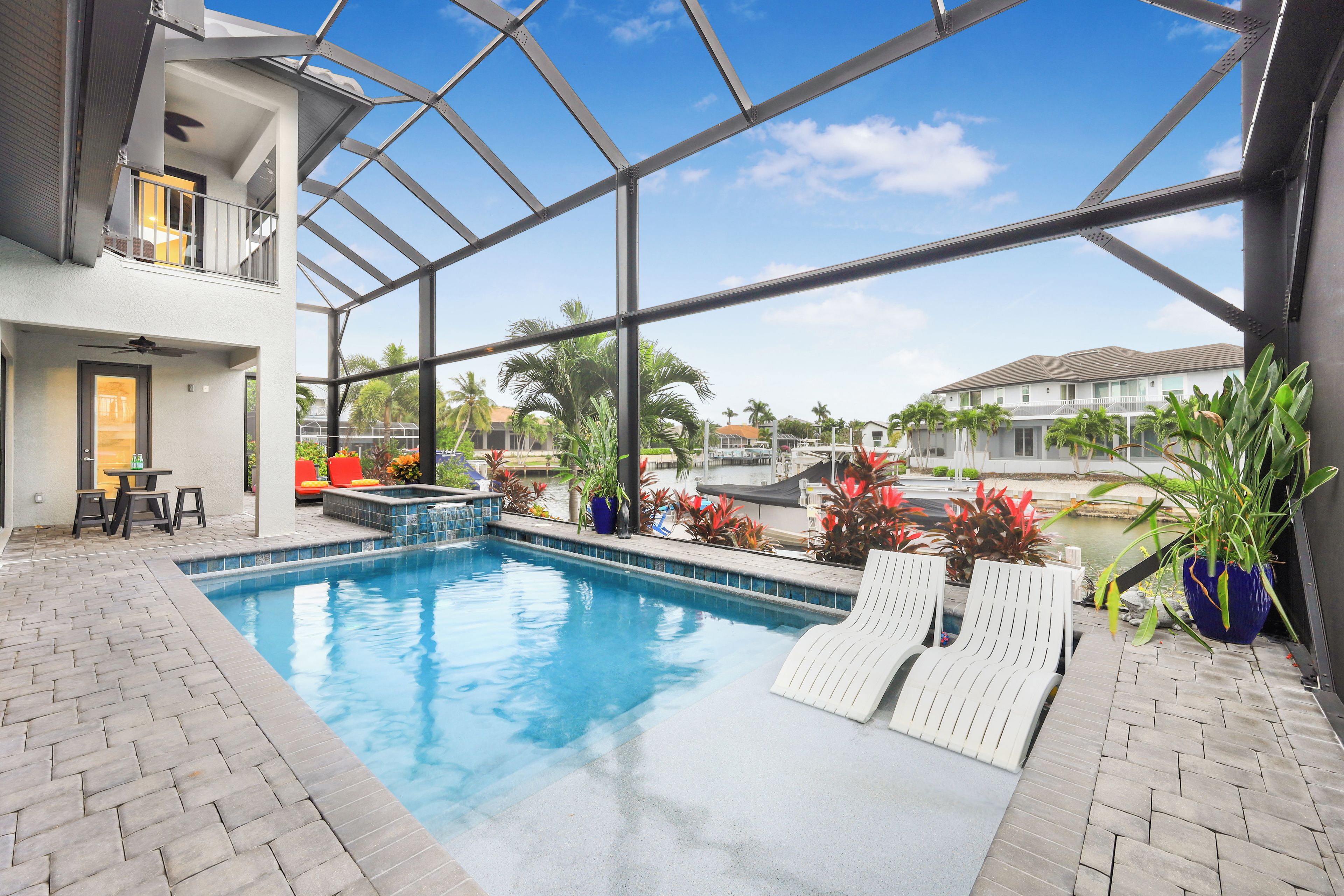 An indoor swimming pool with a clear view of the surrounding neighborhood, including houses and palm trees.