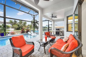 A sunlit patio with a pool, outdoor furniture, and a view of the surrounding area.