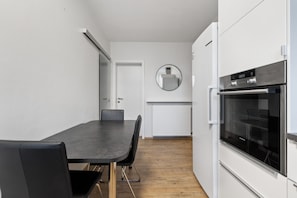 Une cuisine moderne avec des meubles blancs, un plan de travail noir et un four encastré.