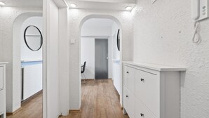 Een hal met witte wanden, houten vloeren en een wit kastje met lades.