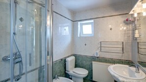 Un baño con ducha de vidrio, inodoro, bidé, lavabo y radiador.