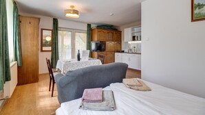 Una habitación con cama, una mesa con silla, televisión y kitchenette.