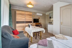 A compact room with a sofa, a dining table, a TV, and a kitchenette. - Studio Apartment in Heviz  3 (Hévíz)