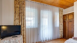 Une pièce avec une télévision posée sur une table, un plancher en bois et une grande armoire en bois.