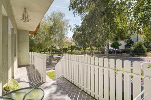A balcony with a white picket fence, a hanging light fixture, and a view of a tree-lined street. - Studio Apartment in Heviz  4 (Hévíz)