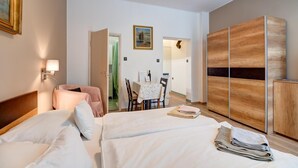 Ein Hotelzimmer mit zwei Betten, einem Esstisch, einem Stuhl, einem Holzschrank und einem Bild an der Wand.
