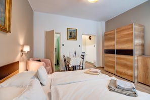 Habitación de hotel con dos camas, una mesa de comedor, una silla, un armario de madera y un cuadro en la pared.