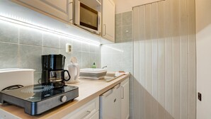 Eine Küche mit Mikrowelle, Kaffeemaschine und Spüle.