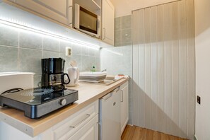 Una cocina con microondas, cafetera y lavabo.
