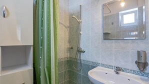 Ein Badezimmer mit Dusche, Waschbecken, Spiegel und Schrank.