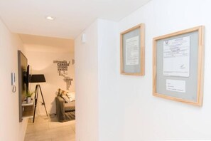 Stylish corridor with a framed certificate, sofa, and wall-mounted TV.