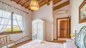 A bedroom with a bed, a wardrobe, a chair, and a window with curtains. - Agriturismo Maramaldo (Castelfiorentino)