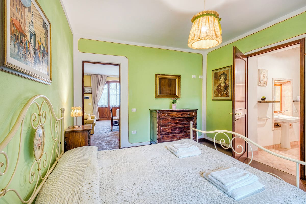 A bedroom with a bed, a dresser, a mirror, and a door leading to a bathroom.