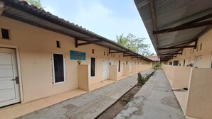 A row of single-room cabins with a sign indicating a cost of 1,000 Malusi Congo. - Hotel O Venus Homestay Syariah Near Universitas Megou Pak Tulang Bawang (Menggala)
