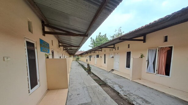 A corridor with multiple rooms, each with a door and a window. There is a sign on the wall and a small plant near one of the doors. - Hotel O Venus Homestay Syariah Near Universitas Megou Pak Tulang Bawang (Menggala)