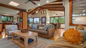 Uma sala de estar ampla com teto de madeira, um sofá, uma mesa de centro e uma área de jantar com cadeiras e mesa.