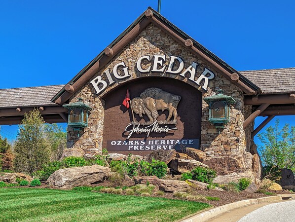 A building with a stone facade, a large sign reading "Big Cedar," and a logo for "Ozarks Heritage Preserve."