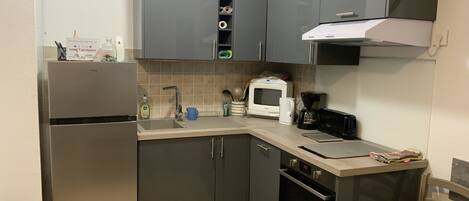 Una cocina compacta equipada con refrigerador, microondas, horno y cafetera.