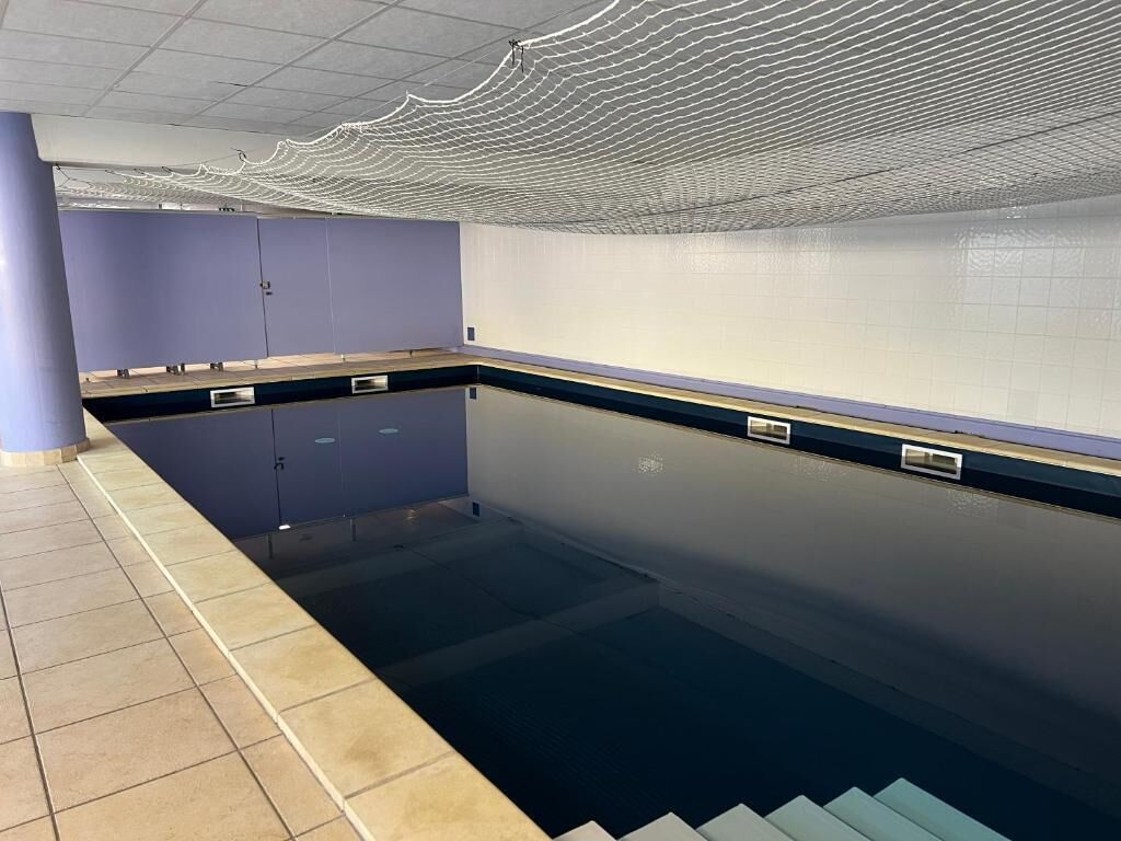 En swimmingpool med ett kaklat golv, en blå vägg och ett tak med ett vågformat mönster.