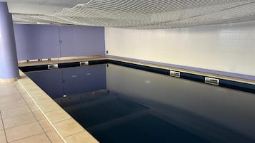 Una piscina con pavimento piastrellato, parete azzurra e soffitto con motivo a onde.