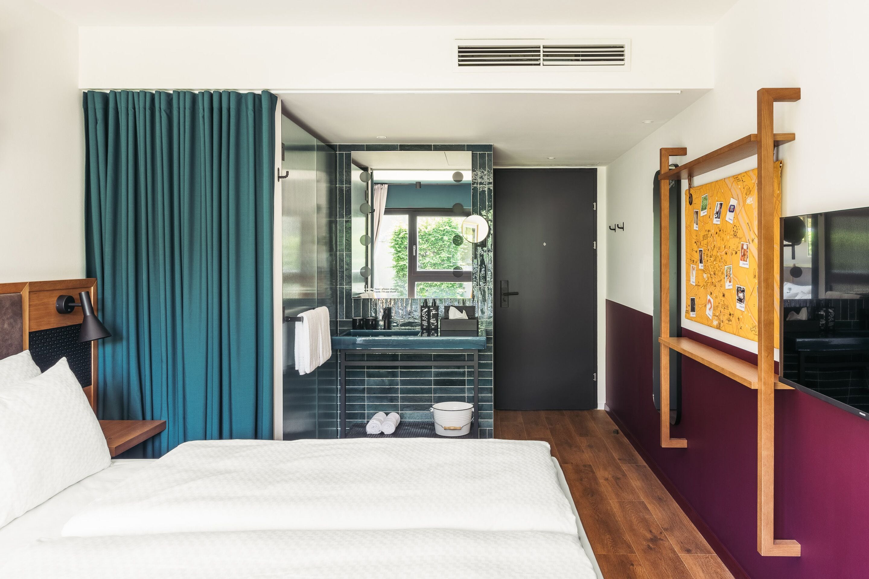 Une chambre d’hôtel avec un lit, une salle de bain avec un miroir, un lavabo et une fenêtre.