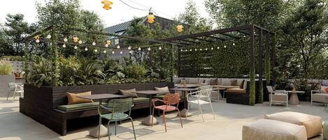 Un patio al aire libre con una pérgola de madera, arreglos de asientos y luces colgantes.