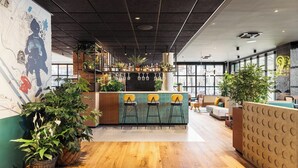 Een moderne bar met krukken, een toonbank en potplanten.