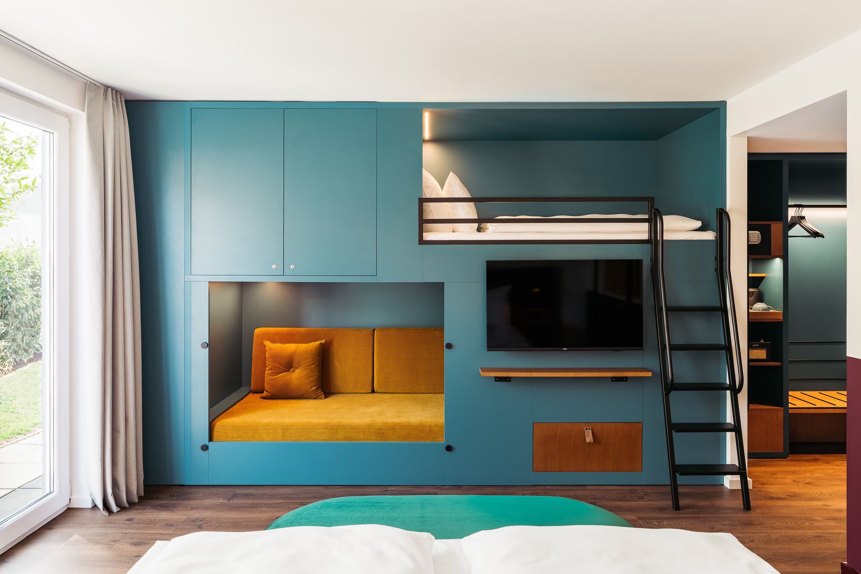 Quarto moderno com cama beliche, sofá, televisão e escada.