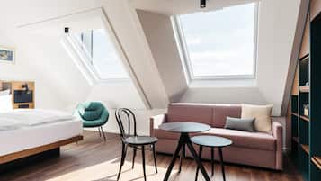 Un dormitorio tipo loft moderno con tragaluces, una cama, un sofá, una silla y una mesita.