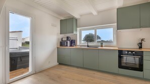 A modern kitchen with green cabinets, a wooden countertop, a built-in oven, and a window providing natural light. - House for 8, with jacuzzi 200m from the beach (La Bernerie-en-Retz)