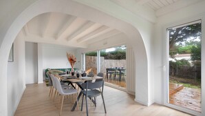 A spacious dining area with a wooden table and chairs, large windows, and an arched ceiling. - House for 8, with jacuzzi 200m from the beach (La Bernerie-en-Retz)