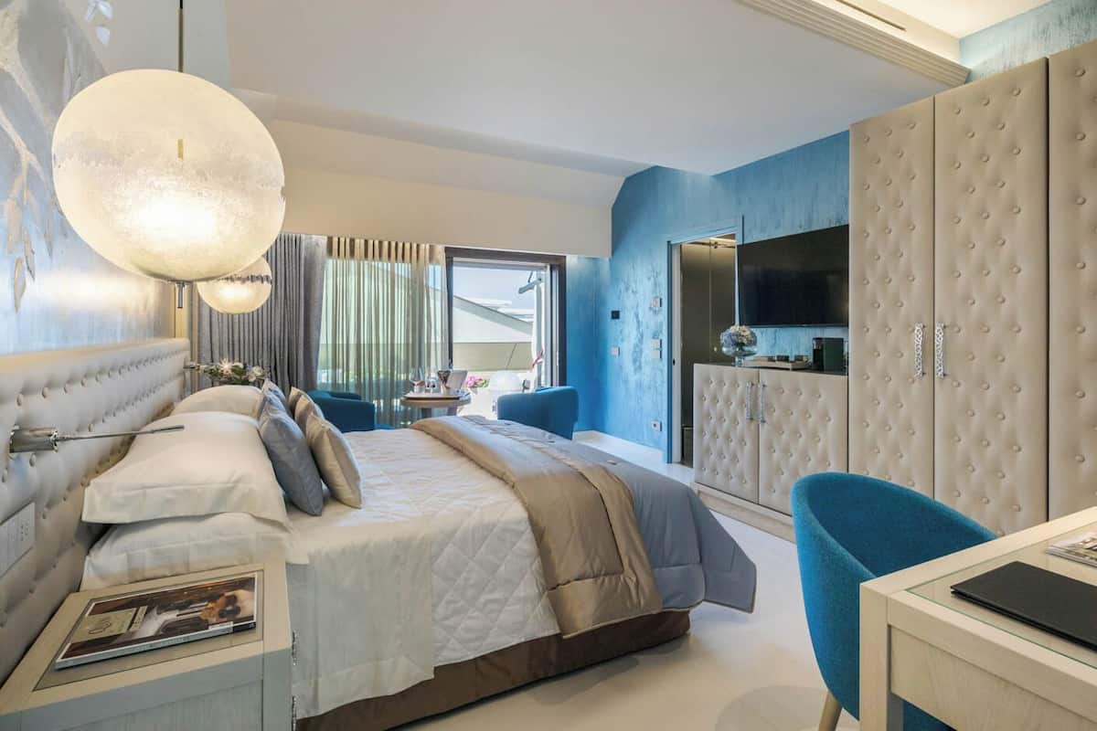 Un dormitorio moderno con una cama grande, un armario capitoné, un escritorio y un ventanal amplio.