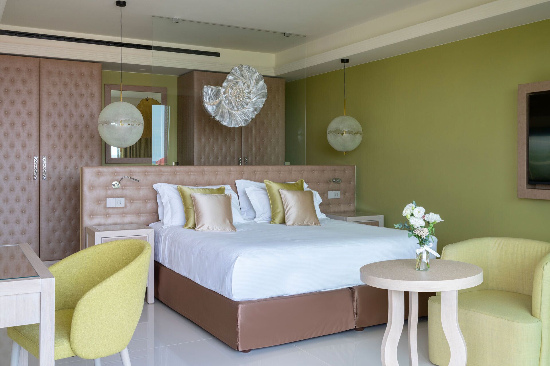 Une chambre moderne avec un grand lit, une table de chevet ronde et deux chaises.