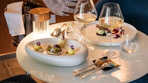 A dining table with a white plate of appetizers, two wine glasses, and a bottle of wine. - Cala Beach Resort (Castiglione della Pescaia)