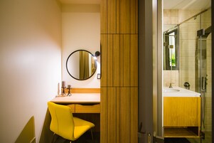 Een badkamer met een houten wastafelmeubel, een spiegel en een douchehoek.