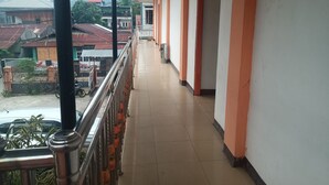 A corridor with a metal railing, tiled floor, and orange-painted walls.