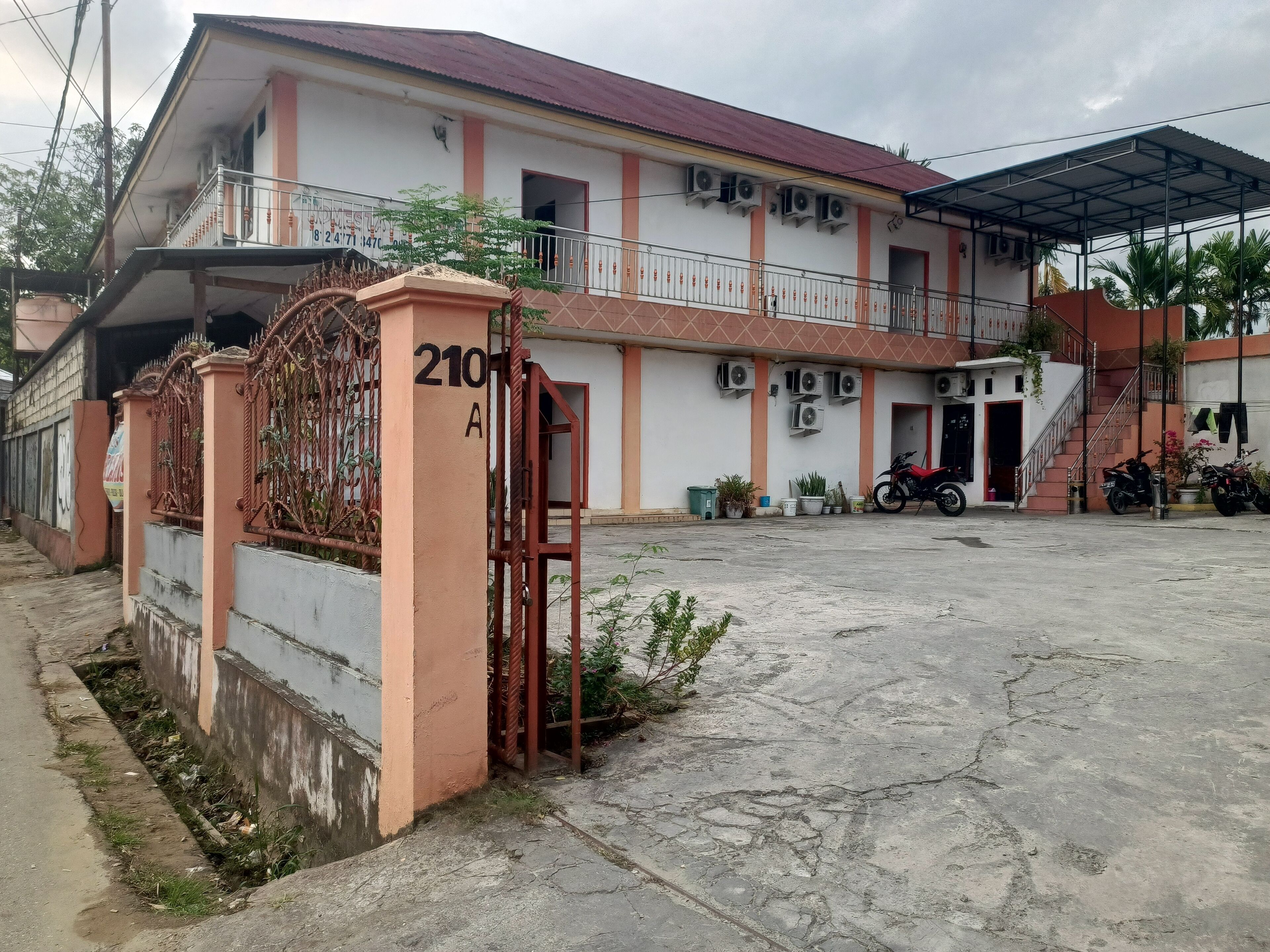 A building with a gated entrance, multiple air conditioning units, and a covered area with stairs.