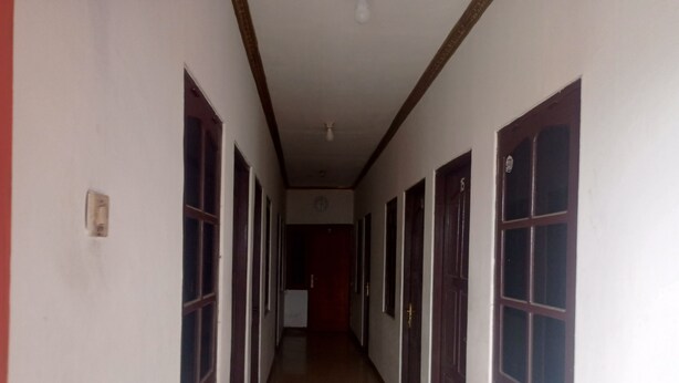 A long, narrow hallway with multiple doors and windows, leading to a room at the end.