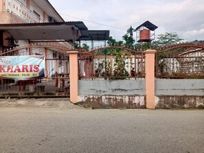 Une entrée fermée par un portail, avec une enseigne indiquant « Kios Kharis » et une clôture en métal.