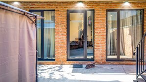 Un bâtiment en briques doté de grandes portes coulissantes en verre, un chat sur le sol et une zone abritée sur la gauche.
