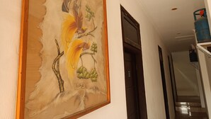 Ein Flur mit einem gerahmten Gemälde, das einen Vogel und einen Baum zeigt, mit dem Schriftzug 'PAPUA'.