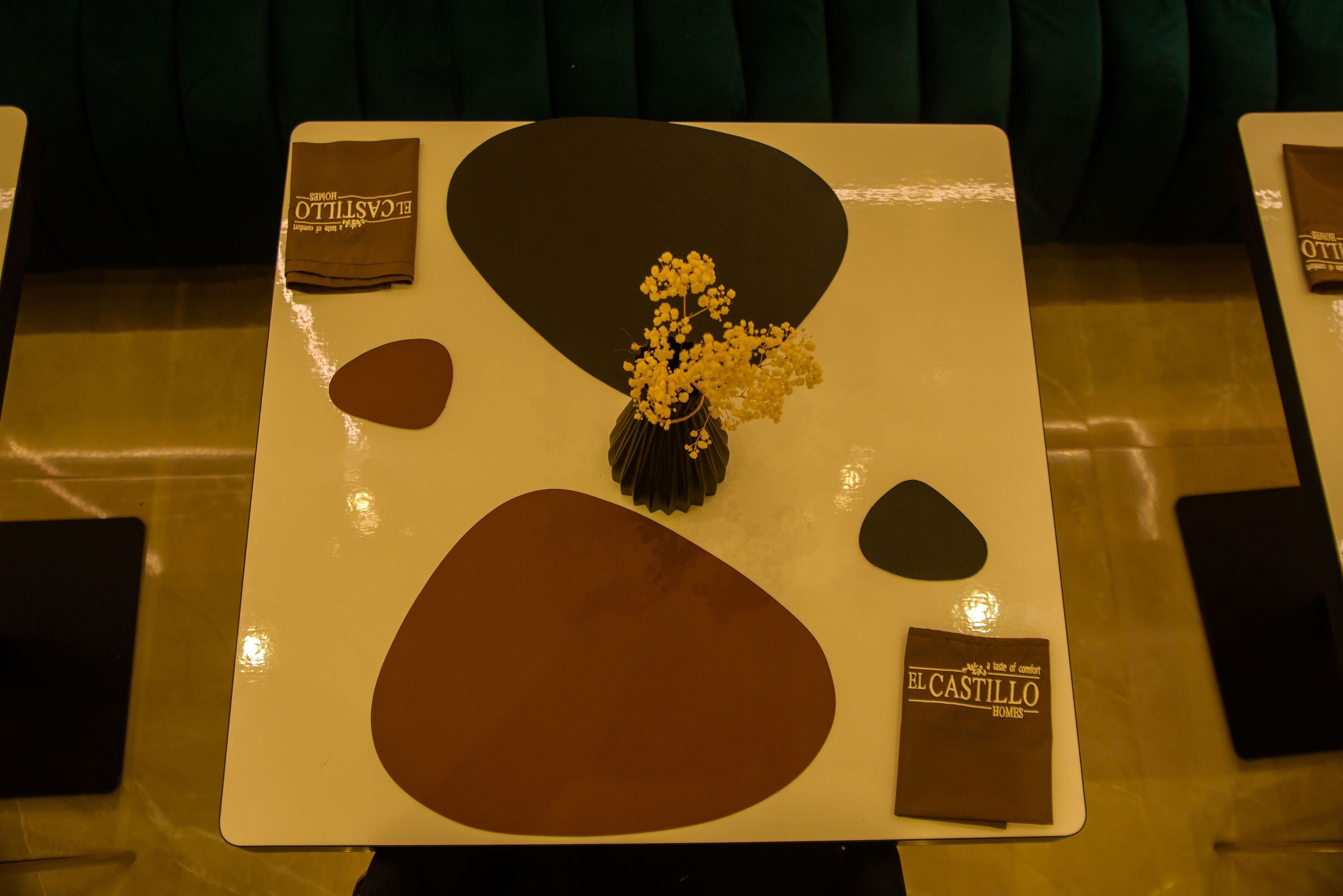 Une table avec un vase de fleurs, une serviette et un petit sac étiqueté « EL CASTILLO HOMES ».