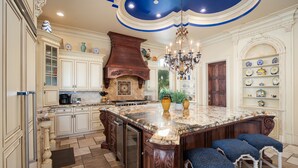 Una cocina amplia con una isla grande, armarios de madera y un techo decorativo.