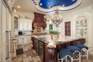 Una cocina amplia con una isla grande, armarios de madera y un techo decorativo.