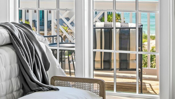 Een kamer met een bed en uitzicht op een balkon met zwembad en zee.