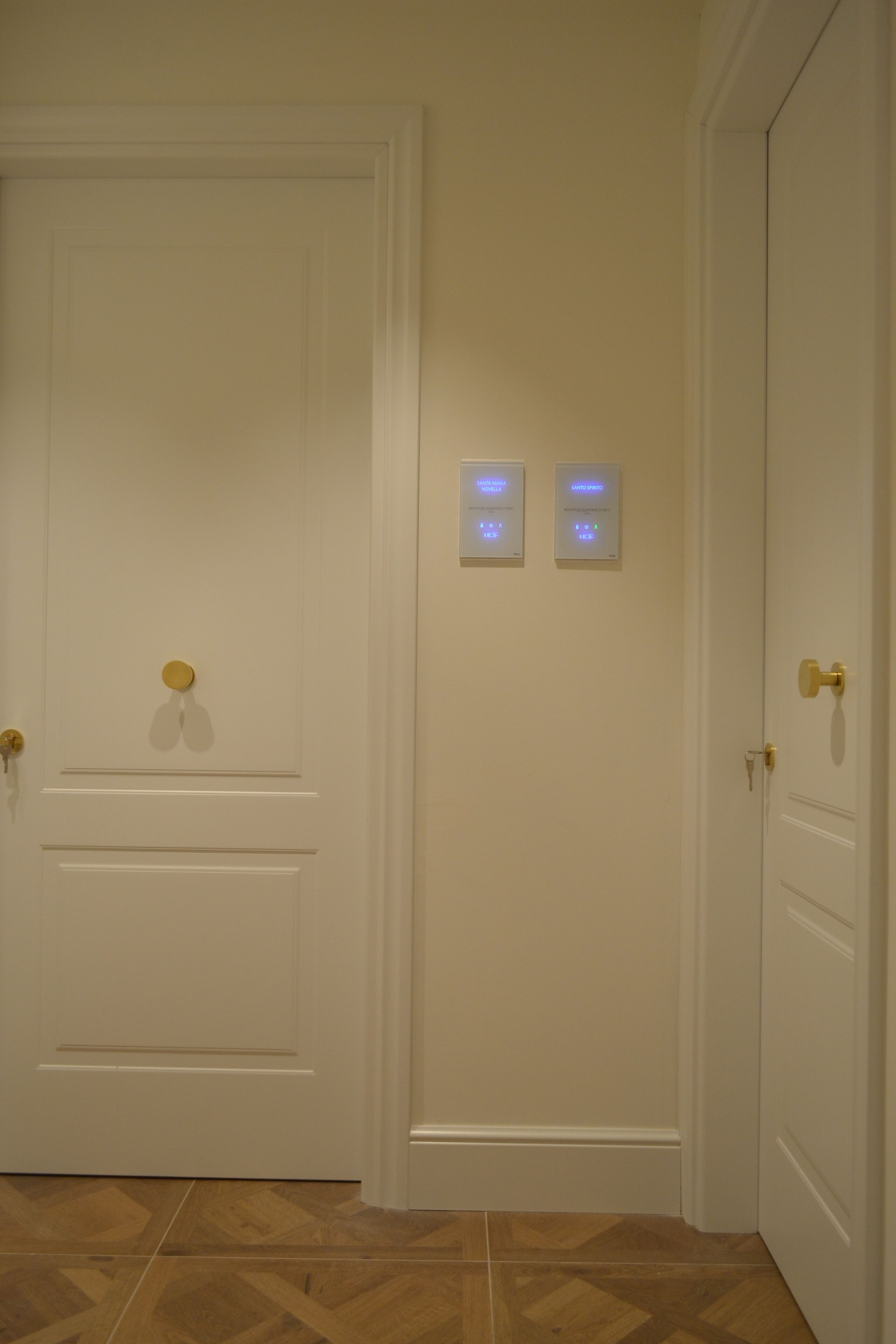 A hallway with a white door, a wall-mounted light switch, and a doorbell.