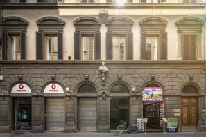 A building with closed shutters, a Vodafone sign, and a tourist information board.